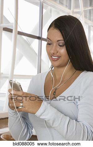 Stock Photography - Hispanic woman listening to mp3 player. Fotosearch