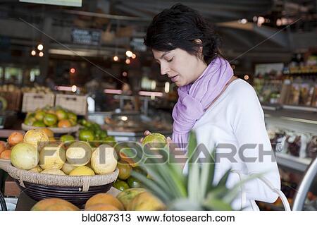 Stock Image - Hispanic woman shopping for fruit. Fotosearch