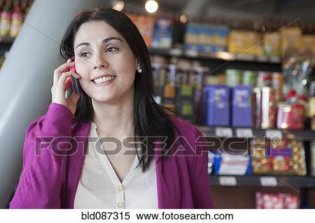 Hispanic woman talking on cell phone in grocery store View Large Photo Image Stock Photography - Hispanic woman talking on cell phone in grocery store. Fotosearch