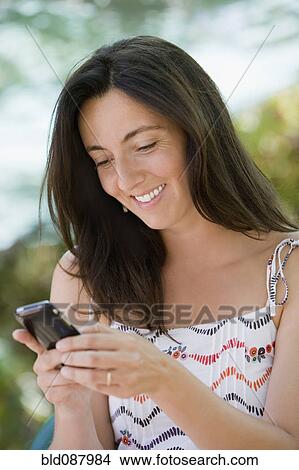 Picture - Hispanic woman text messaging on cell phone. Fotosearch