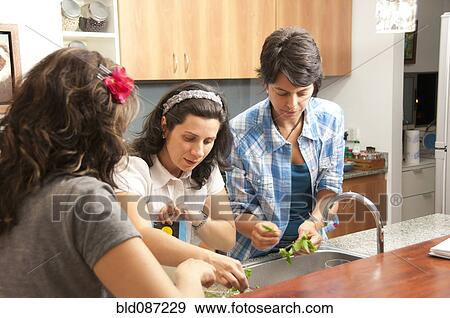 Stock Photo - Hispanic women preparing food together. Fotosearch