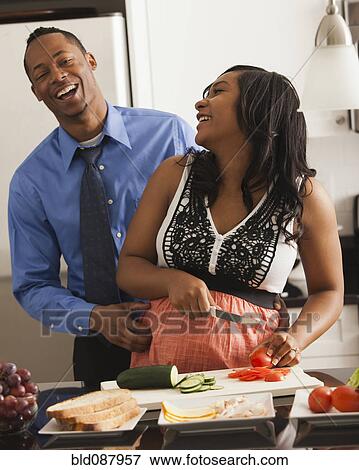 Stock Photo - Laughing couple cooking together in kitchen. Fotosearch