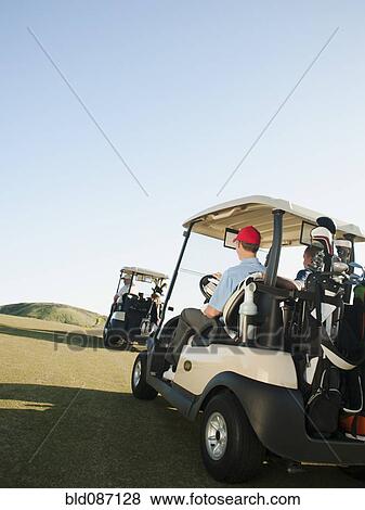Men driving golf carts on golf course View Large Photo Image Stock Photo - Men driving golf carts on golf course. Fotosearch