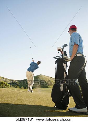 Stock Image - Men playing golf on golf course. Fotosearch
