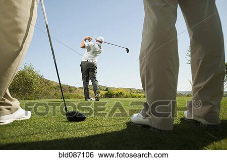 Stock Photograph - Men playing golf together on golf course. Fotosearch