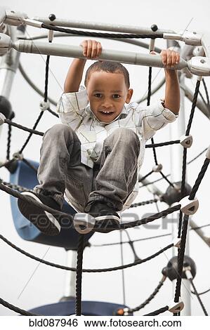 Mixed race boy climbing on structure in playground View Large Photo Image Stock Photograph - Mixed race boy climbing on structure in playground. Fotosearch