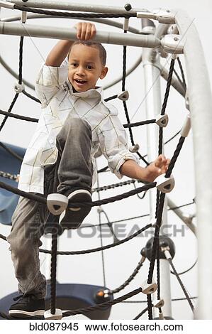 Mixed race boy climbing on structure in playground View Large Photo Image Stock Photography - Mixed race boy climbing on structure in playground. Fotosearch