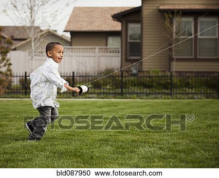 Stock Image - Mixed race boy flying kite. Fotosearch