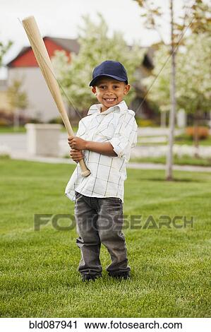 Stock Image - Mixed race boy playing baseball in grass. Fotosearch