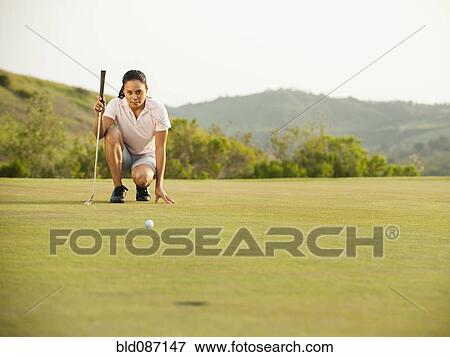 Mixed race woman checking ground on golf course View Large Photo Image Stock Photo - Mixed race woman checking ground on golf course. Fotosearch