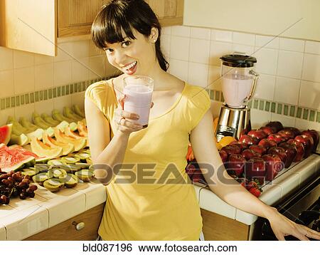 Mixed race woman drinking smoothie in kitchen View Large Photo Image Stock Photograph - Mixed race woman drinking smoothie in kitchen. Fotosearch