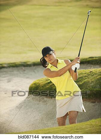 Mixed race woman hitting golf ball out of bunker View Large Photo Image Picture - Mixed race woman hitting golf ball out of bunker. Fotosearch