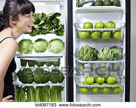Mixed race woman looking at green vegetables in refrigerator View Large Photo Image Stock Image - Mixed race woman looking at green vegetables in refrigerator. Fotosearch