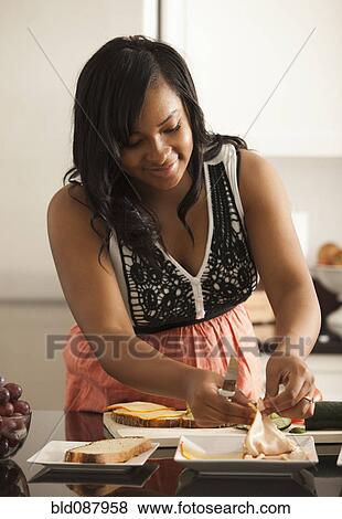 Stock Photo - Mixed race woman making sandwiches in kitchen. Fotosearch