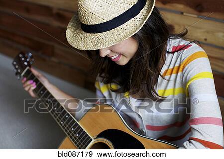 Stock Photo - Mixed race woman playing guitar. Fotosearch
