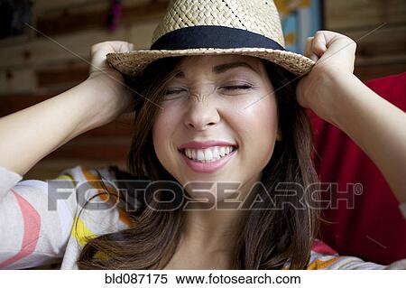 Stock Photography - Mixed race woman putting on hat. Fotosearch