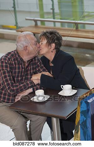 Stock Photo - Senior Hispanic couple kissing in cafe. Fotosearch