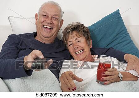 Senior Hispanic couple laying in bed watching television View Large Photo Image Stock Photo - Senior Hispanic couple laying in bed watching television. Fotosearch