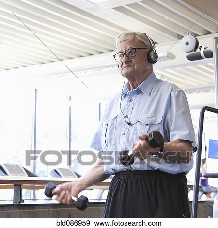 Stock Photo - Senior man lifting weights in health club. Fotosearch