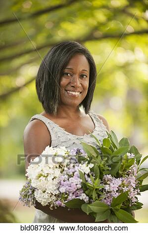 Picture - Smiling African American woman holding bouquet of flowers. Fotosearch