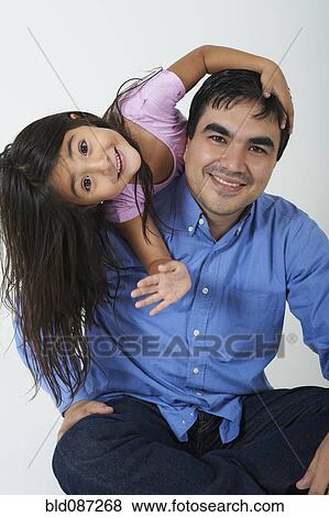 Stock Photo - Smiling Hispanic girl leaning on father. Fotosearch