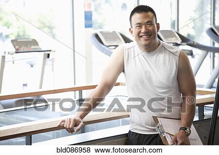 Smiling man with clipboard standing in health club View Large Photo Image Stock Photo - Smiling man with clipboard standing in health club. Fotosearch