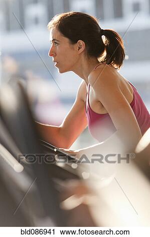 Stock Image - Woman exercising in health club. Fotosearch