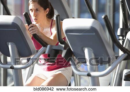 Stock Image - Woman exercising in health club. Fotosearch