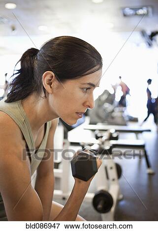 Stock Photo - Woman lifting weights in health club. Fotosearch