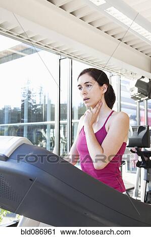Woman on treadmill checking her pulse View Large Photo Image Stock Image - Woman on treadmill checking her pulse. Fotosearch