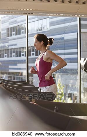 Stock Image - Woman running on treadmill in health club. Fotosearch