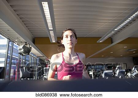 Woman running on treadmill in health club View Large Photo Image Stock Photo - Woman running on treadmill in health club. Fotosearch