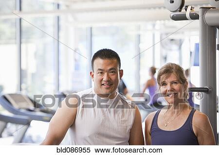 Woman standing with personal trainer in health club View Large Photo Image Stock Photography - Woman standing with personal trainer in health club. Fotosearch