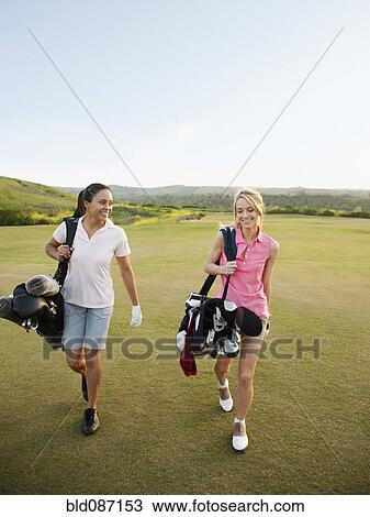 Women carrying golf bags on golf course View Large Photo Image Stock Image - Women carrying golf bags on golf course. Fotosearch