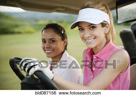 Stock Photograph - Women driving golf cart on golf course. Fotosearch