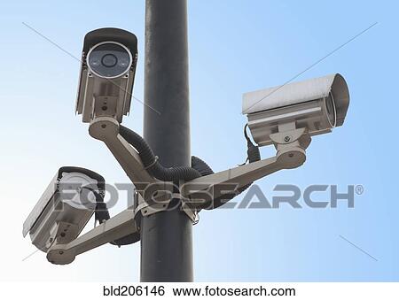 Stock Photograph - A metal post with a gantry and traffic cameras facing in three different directions. Fotosearch