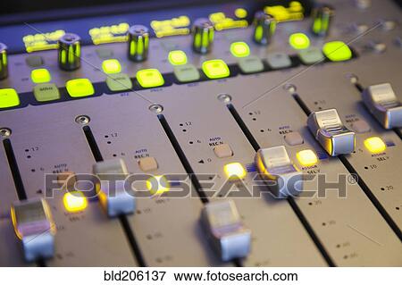 Stock Photo - A sound board with lighted controls in a home recording studio. Fotosearch