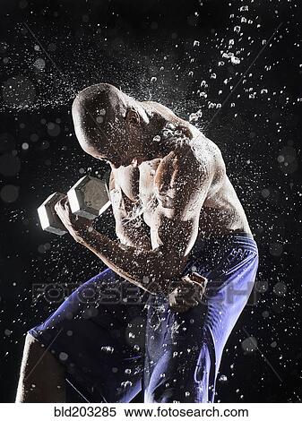 Stock Photography - African American athlete lifting weights in rain. Fotosearch