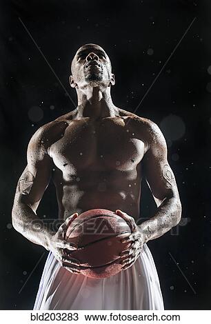 Stock Image - African American basketball player standing under lights. Fotosearch