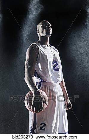 Stock Photo - African American basketball player standing under lights. Fotosearch