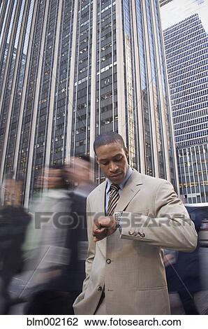 Stock Image - African American businessman checking watch. Fotosearch
