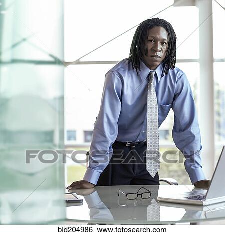 Stock Photograph - African American businessman leaning over desk. Fotosearch