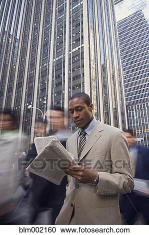 Stock Image - African American businessman reading newspaper. Fotosearch