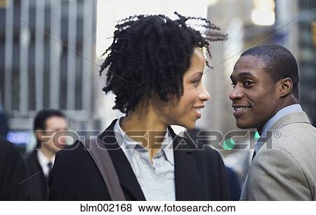 Stock Photo - African American businesswoman smiling at businessman on street. Fotosearch