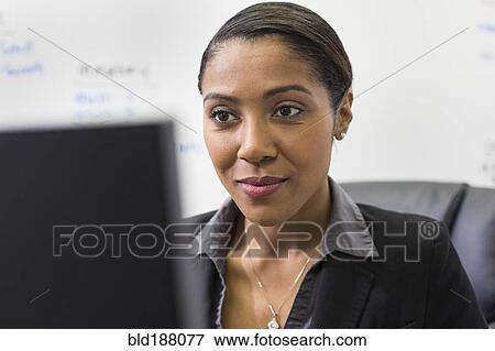 Stock Photo - African American businesswoman using computer in office. Fotosearch
