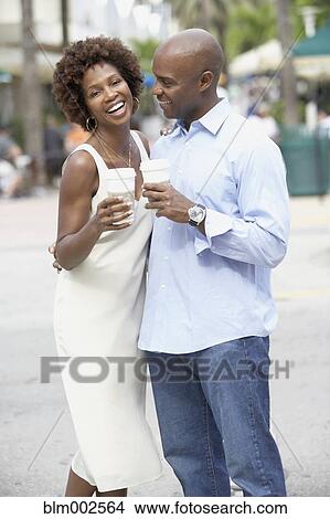 Picture - African American couple drinking take out coffee. Fotosearch