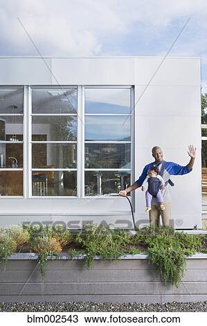 African American father holding baby and watering lawn View Large Photo Image Stock Image - African American father holding baby and watering lawn. Fotosearch