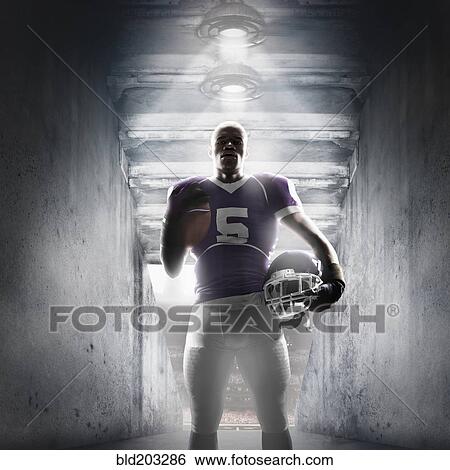 Stock Photograph - African American football player standing in hallway. Fotosearch
