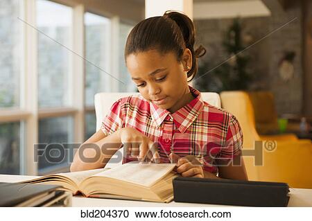 Stock Image - African American girl reading at table. Fotosearch