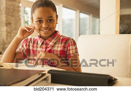 Stock Image - African American girl reading at table. Fotosearch